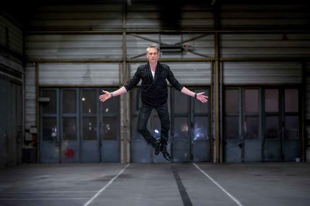 Magician and illusionist performing a jump in an industrial setting.